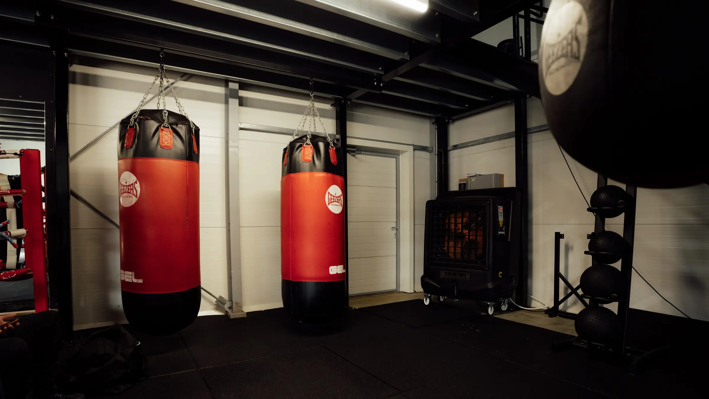 Two heavy bags and a speed bag beside the rings in the boxing gym at BoxCross UK