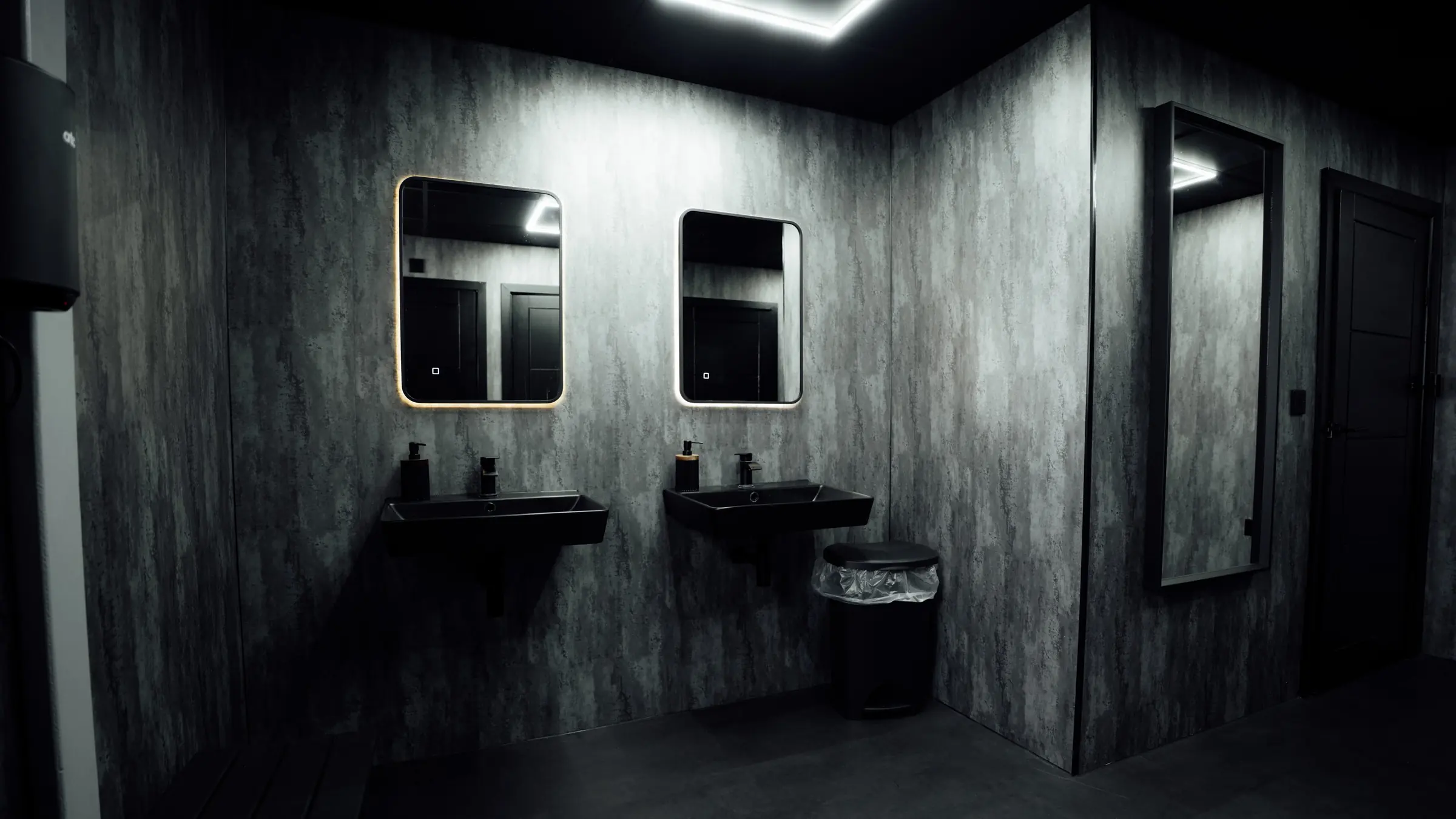 Backlit mirrors above the basins in the gents
