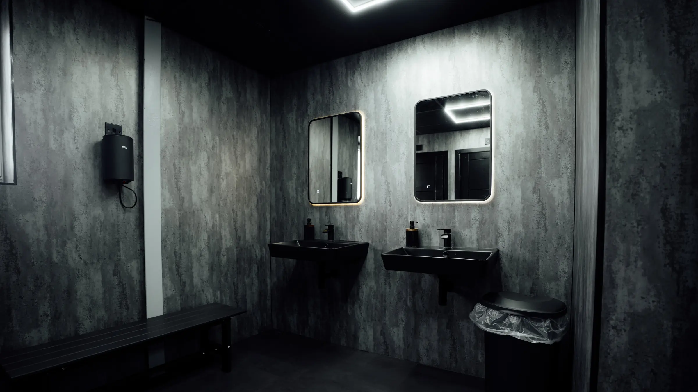 The gents changing room with backlit mirrors and black basins