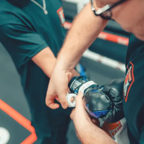 Hands being wrapped and gloved before a boxing session