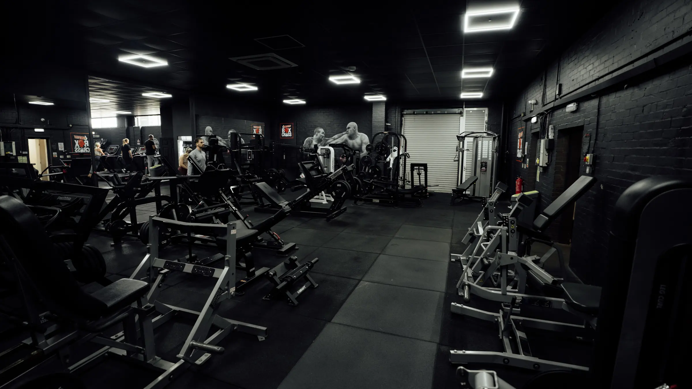 The leg room at BoxCross UK Wisbech, with the hack squat, leg extension, leg curl and plate-loaded leg machines under the boxing murals
