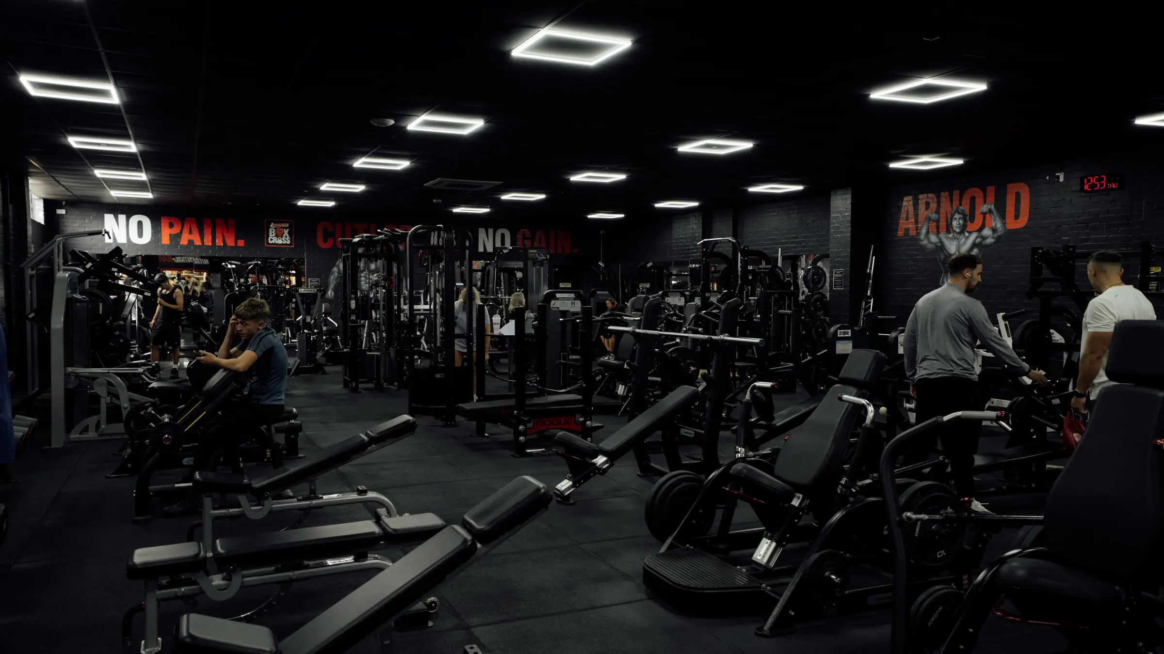 Members training across the main floor beneath the No Pain and Arnold murals