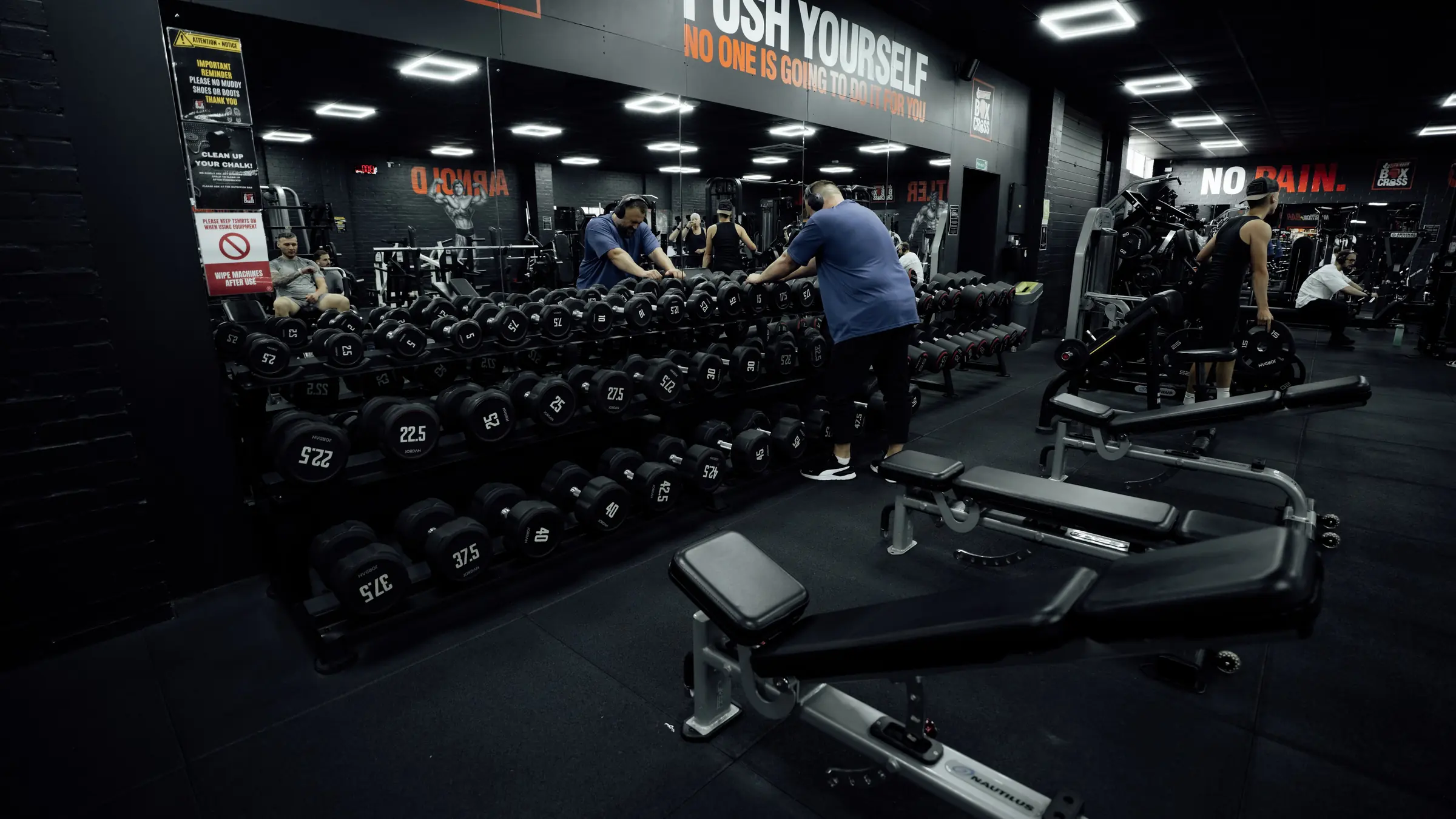 The dumbbell rack on the main floor with members training behind it