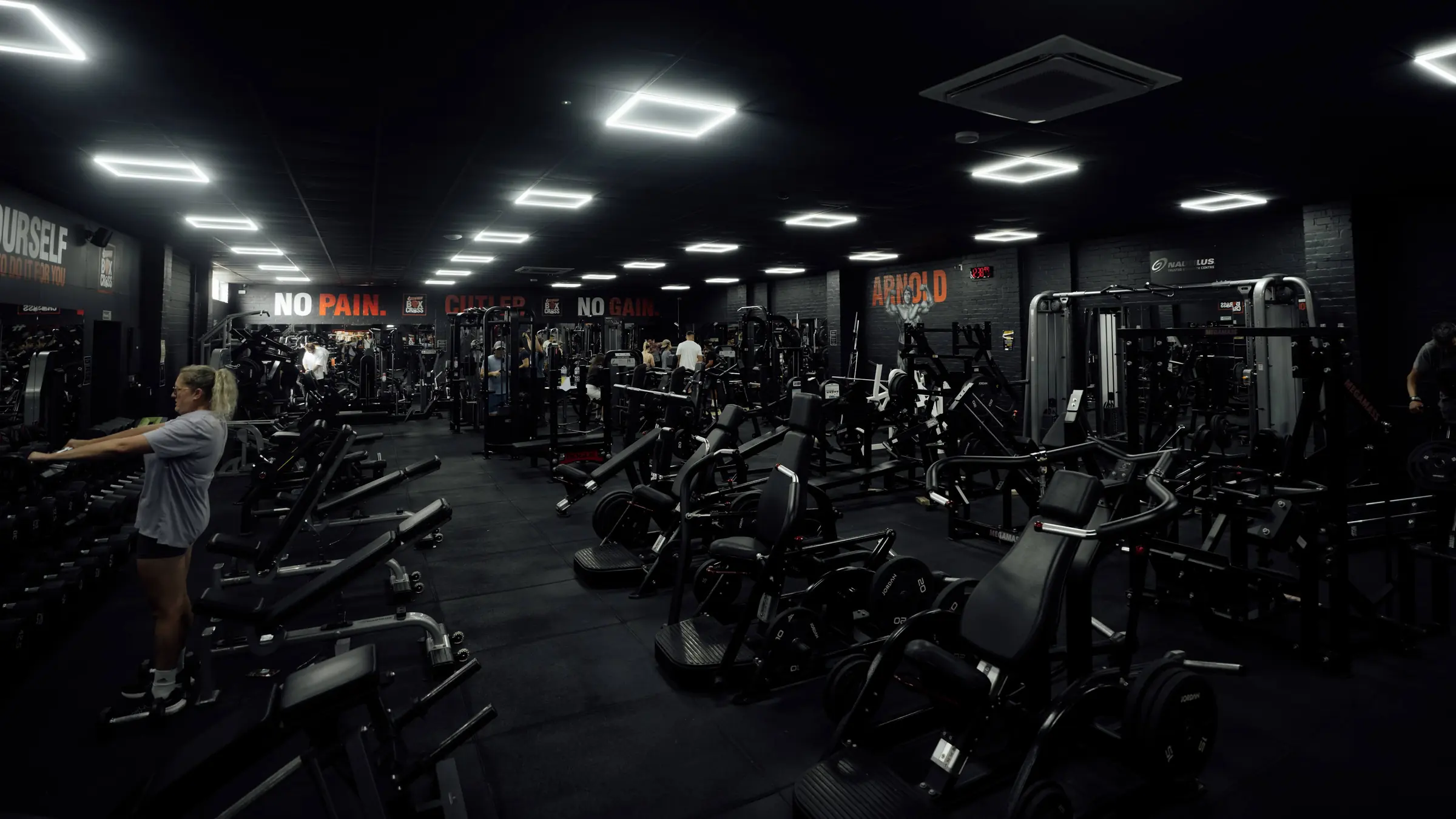 A member at the dumbbell rack with the floor open behind her