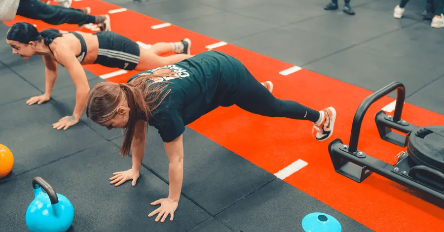 A member holding a plank on the red functional track during a class