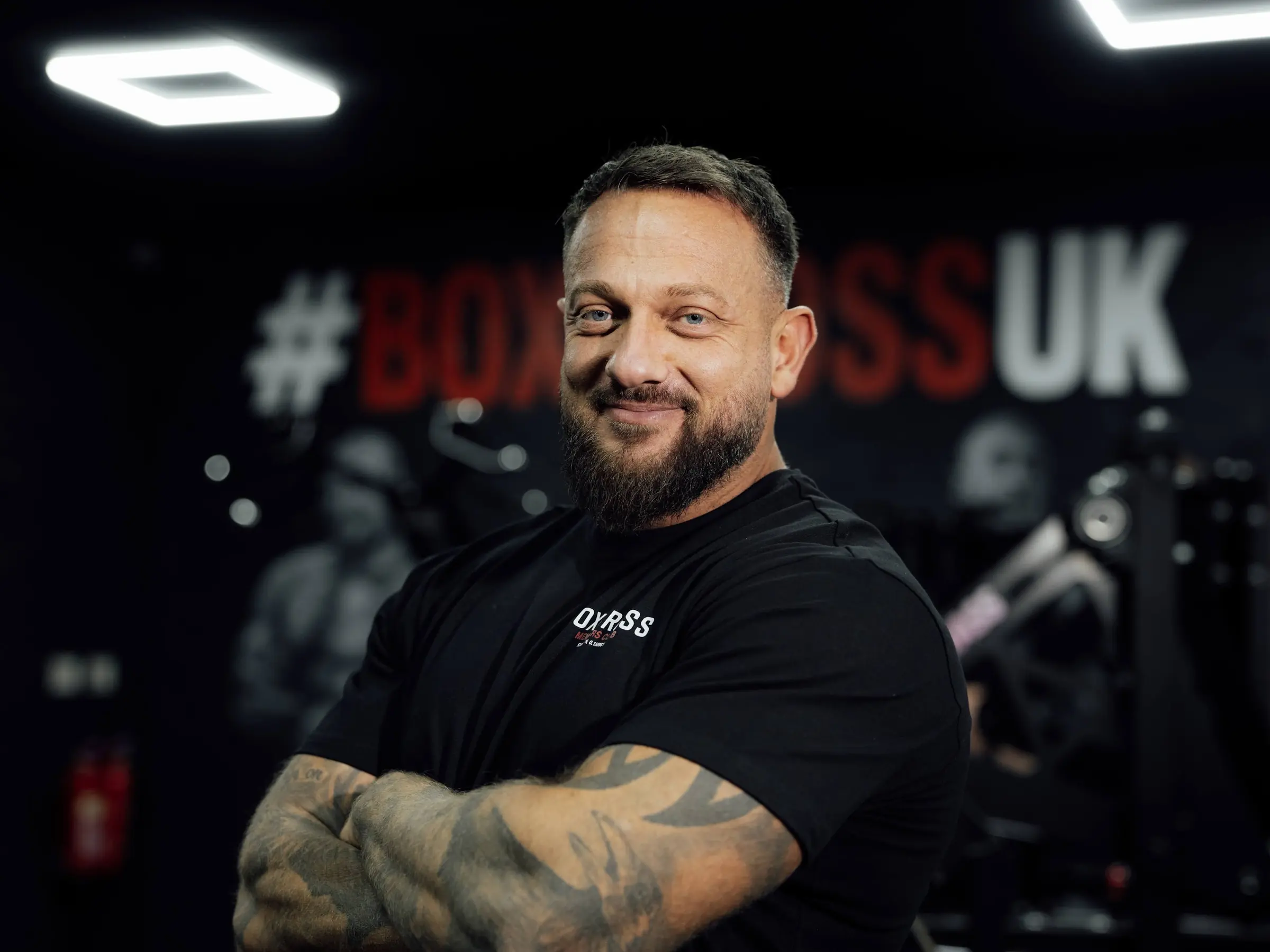 Dave Carse, personal trainer at BoxCross UK Wisbech, arms folded in front of the #BOXCROSSUK mural