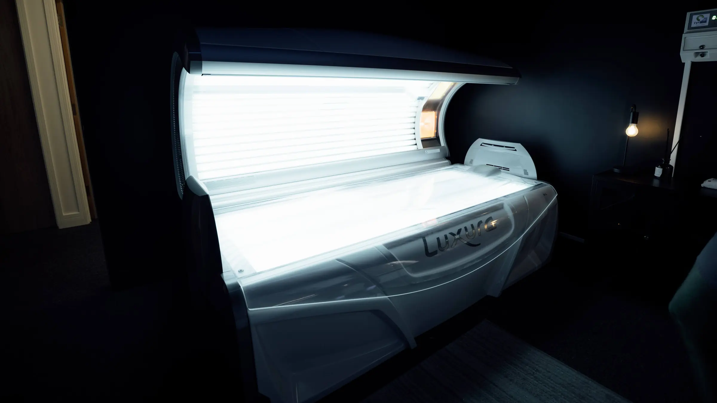 A Luxura lay-down sunbed open and lit in the tanning studio