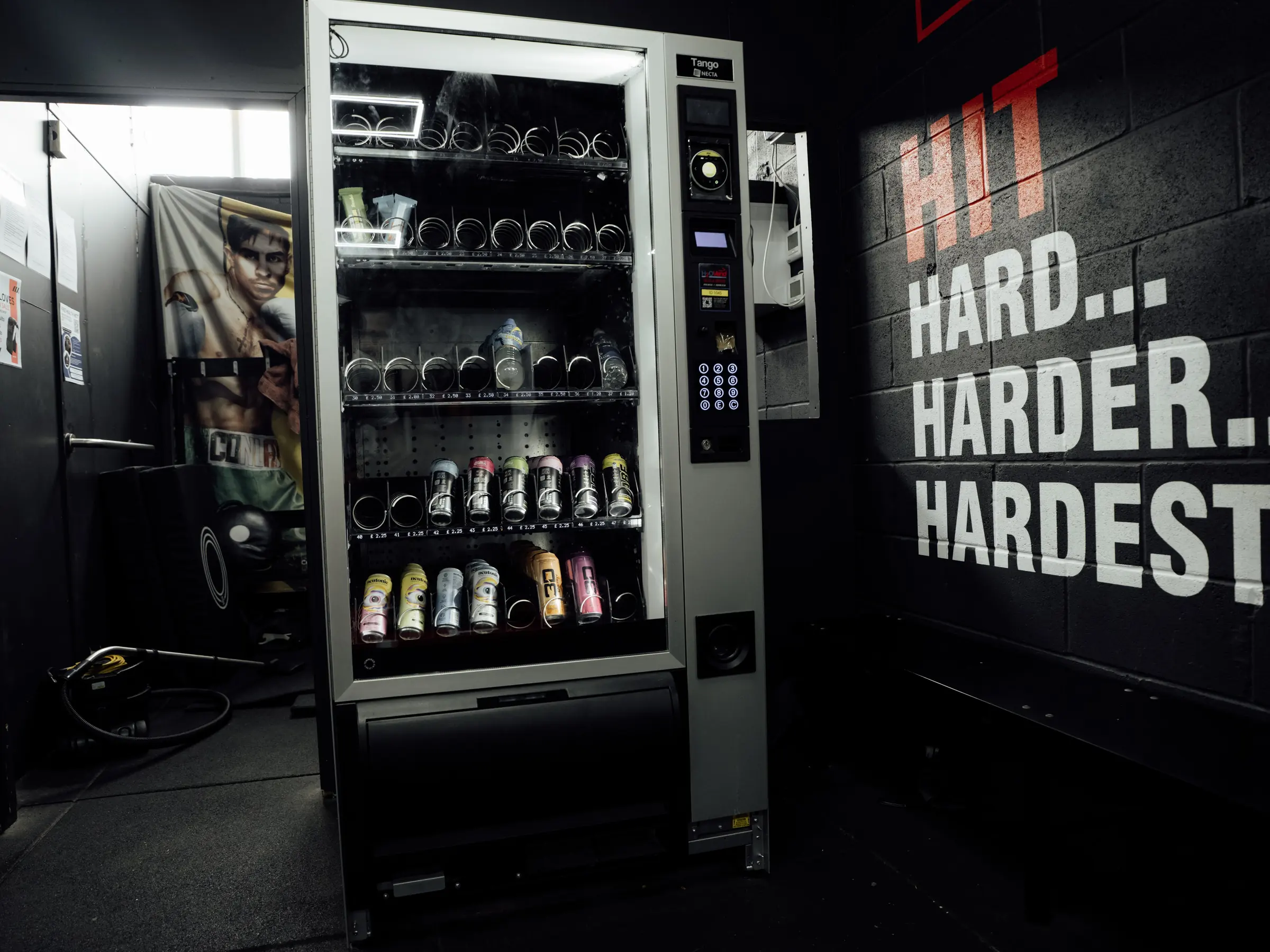 The vending machine beside the Hit Hard Harder Hardest wall lettering