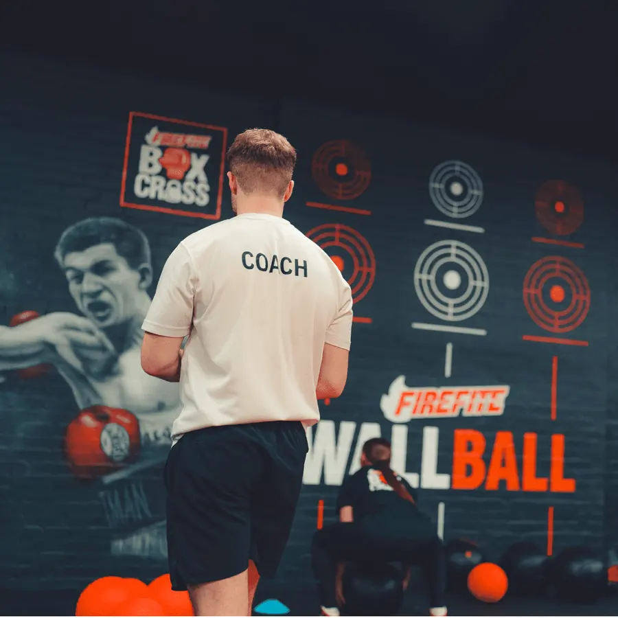 A coach in front of the wall ball target wall at BoxCross
